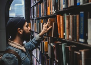Un homme parcourant un rayon dans une librairie.